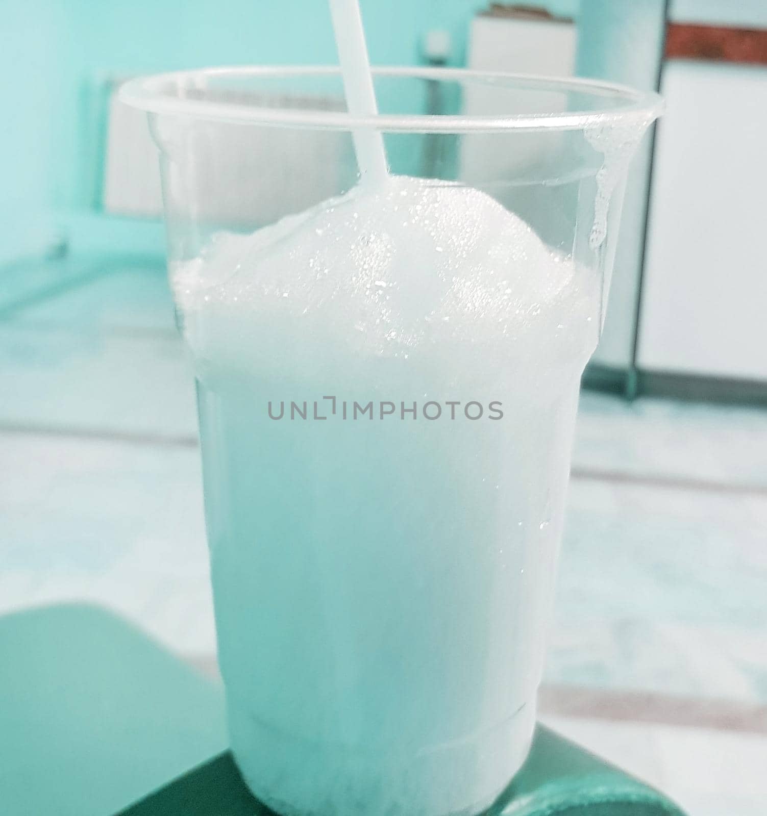 Transparent glass with foam and oxygen cocktail with a straw, blue tinted.