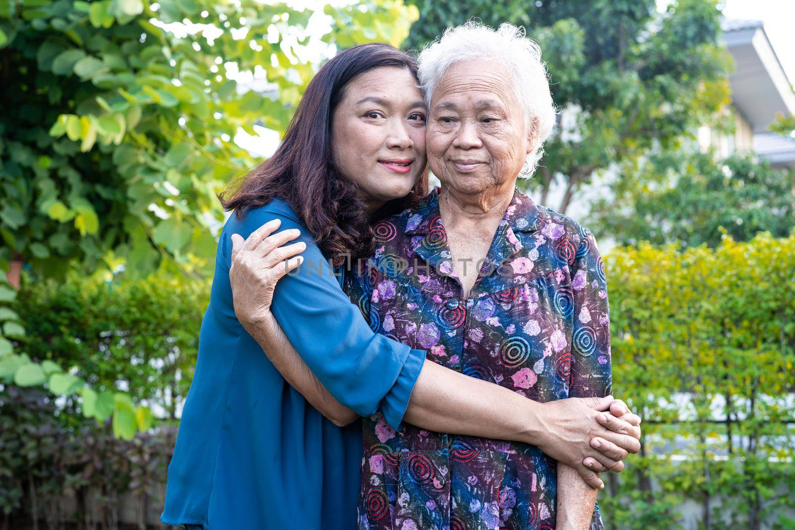 Asian elderly woman with caregiver walking with happy in nature park. by pamai