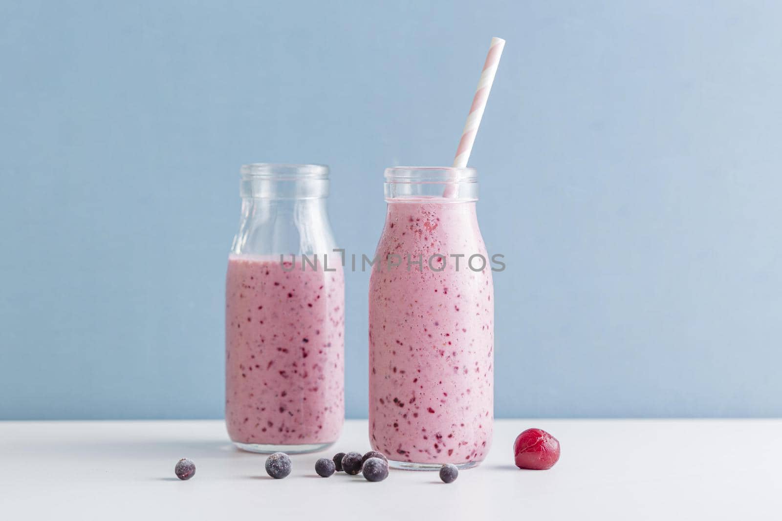 front view pink smoothie bottles with blueberries. High quality beautiful photo concept by Zahard