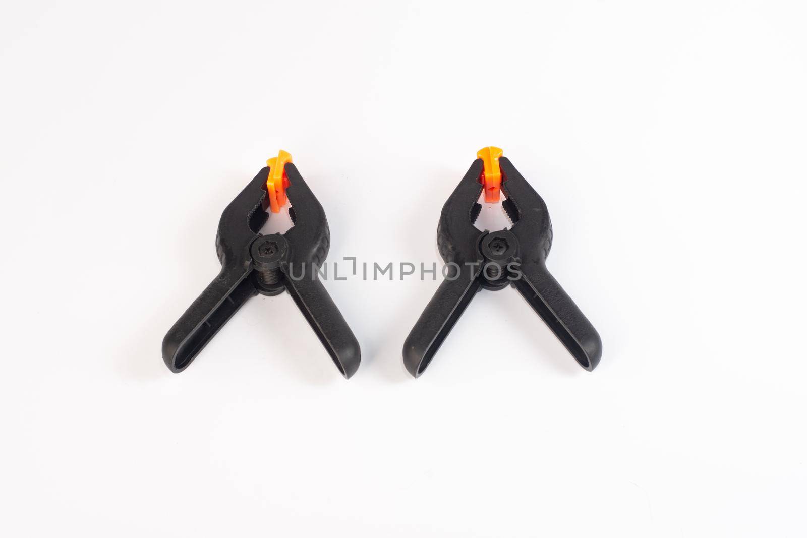 Two black construction clothespins on a white background. close-up
