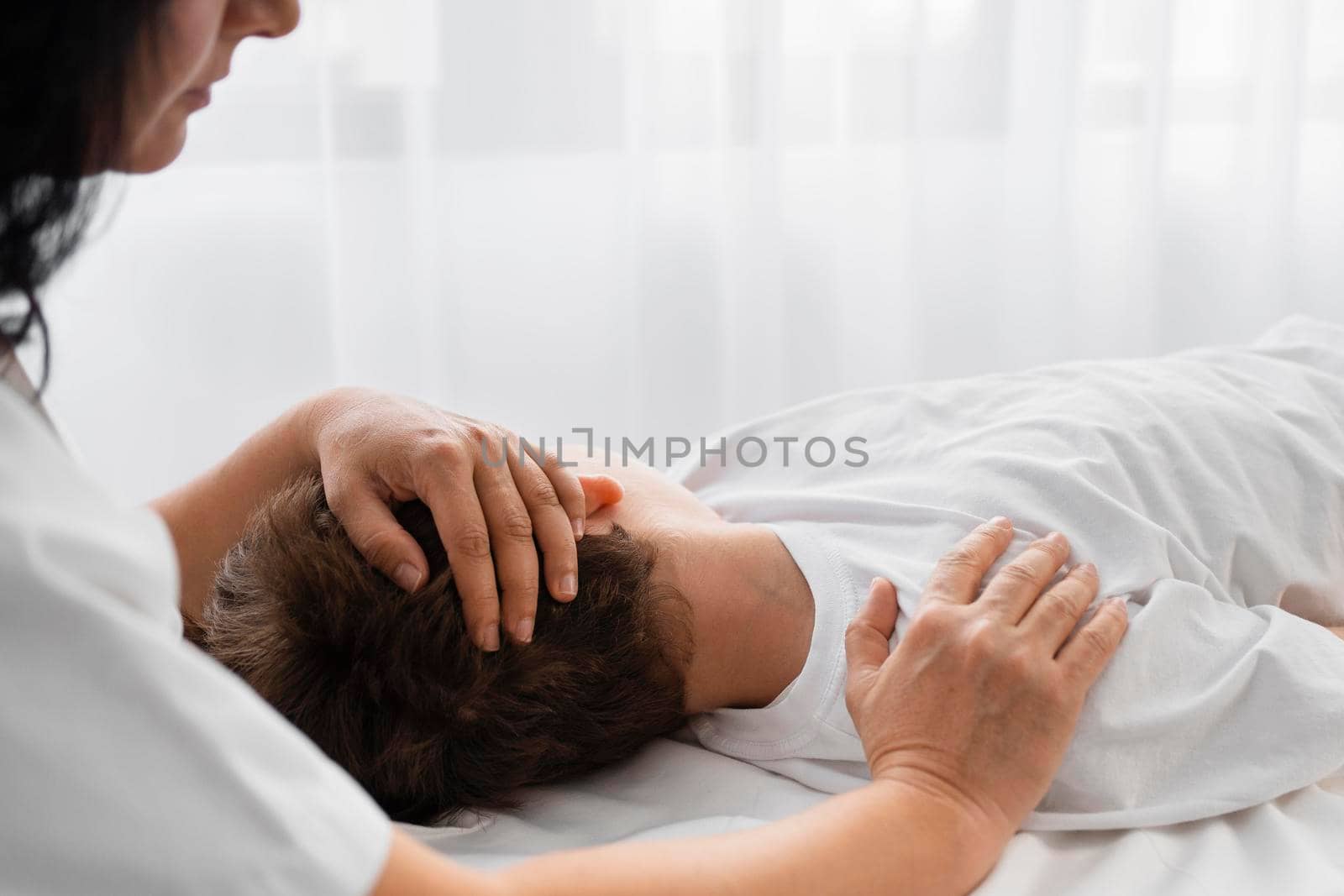 female osteopathist treating boy by massaging him. Beautiful photo