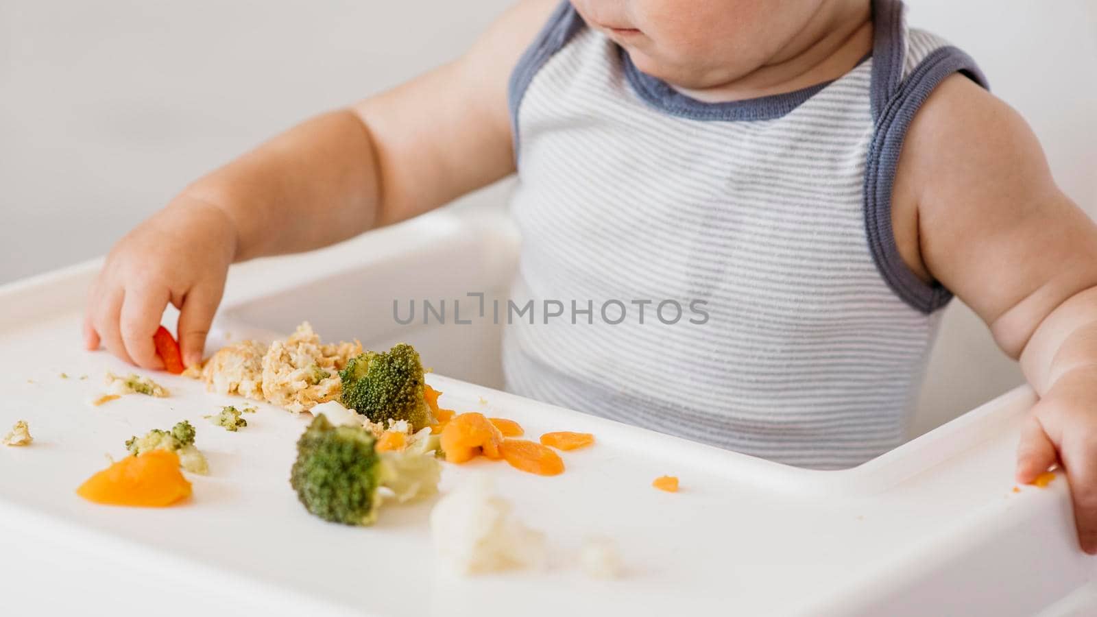 cute baby boy highchair choosing what eat. High quality photo by Zahard