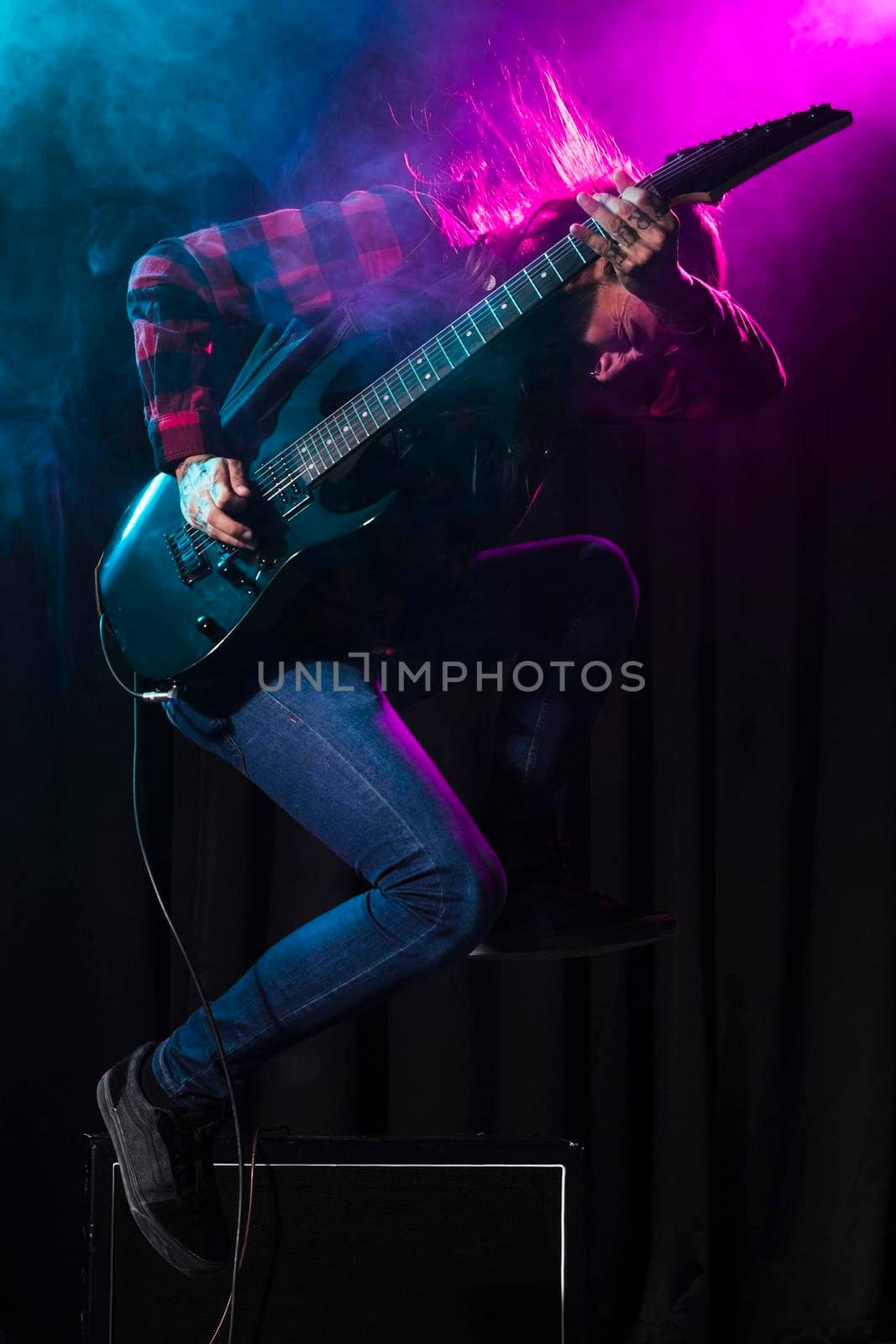 artist playing guitar jumping sideways. High resolution photo