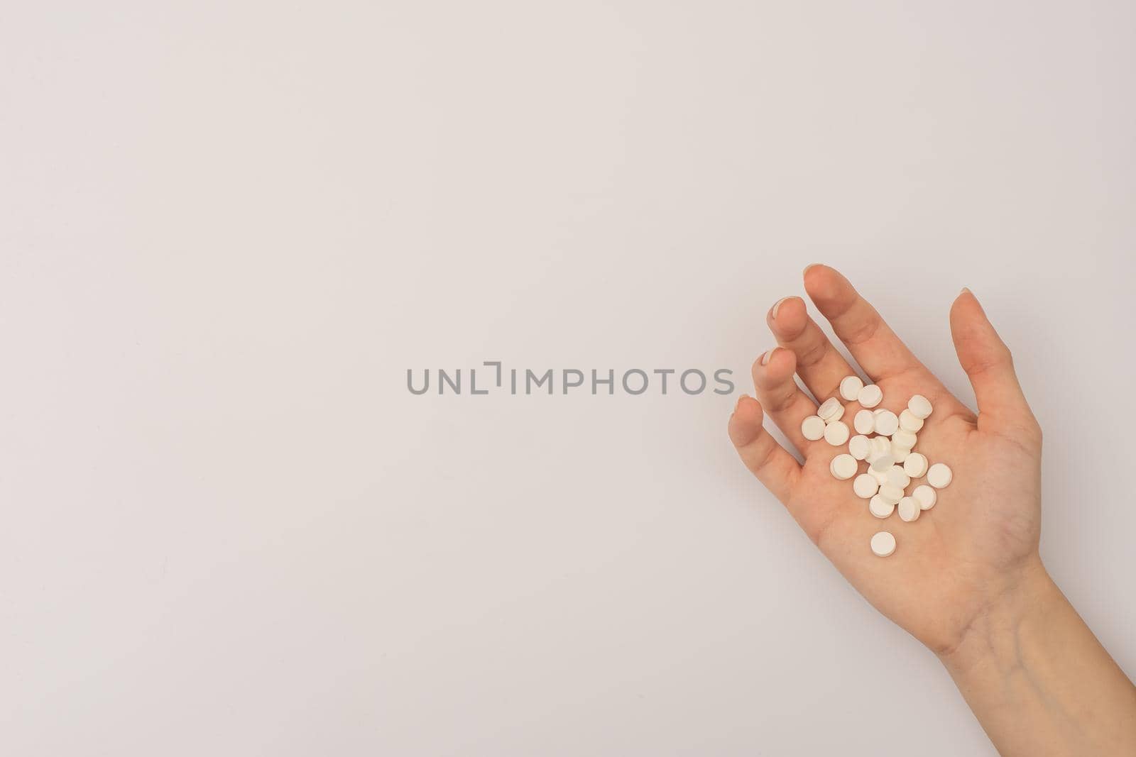 handful of white pills in the palm of your hand on a white background. mock up