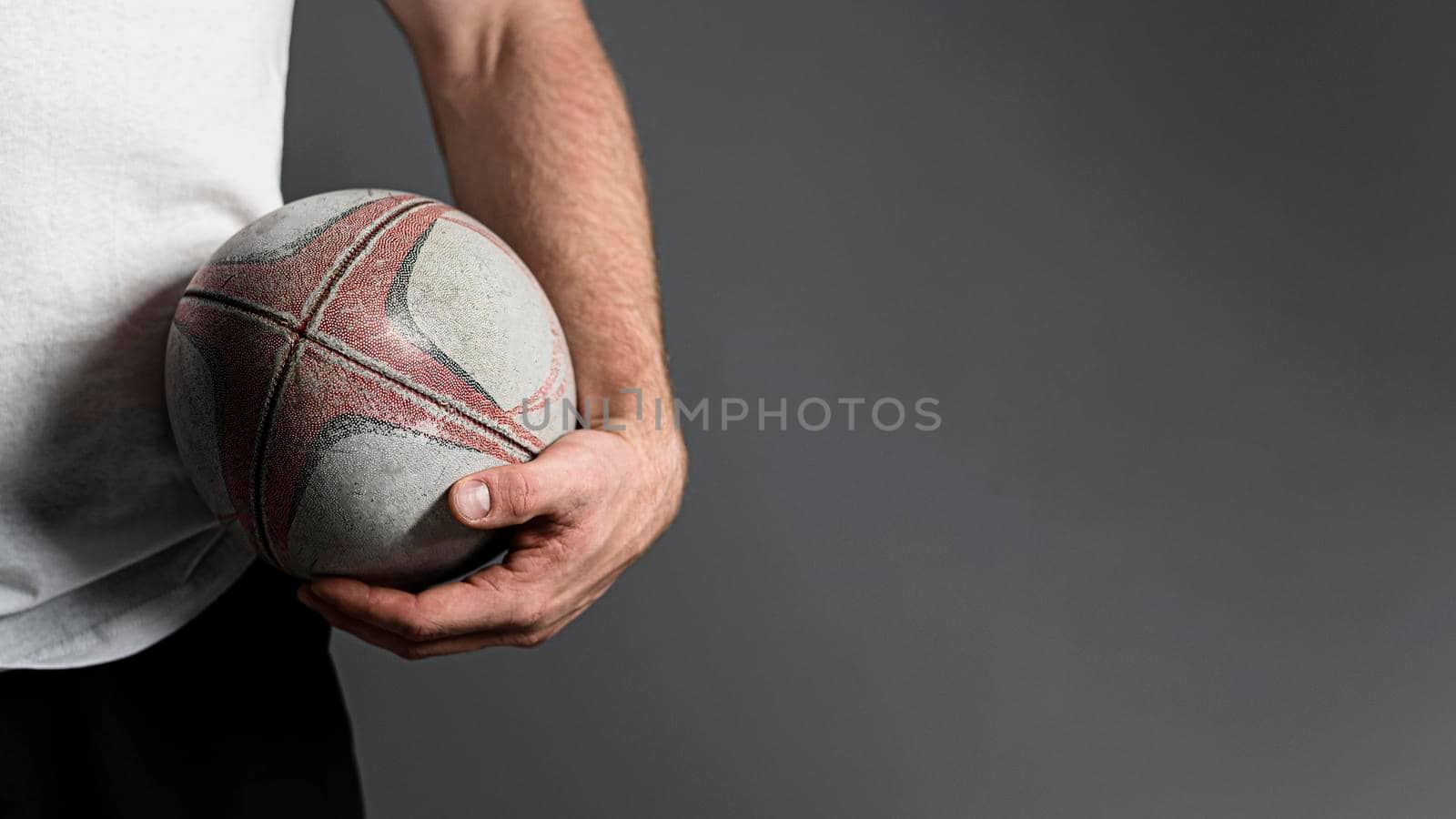 front view male rugby player holding ball hip with copy space by Zahard