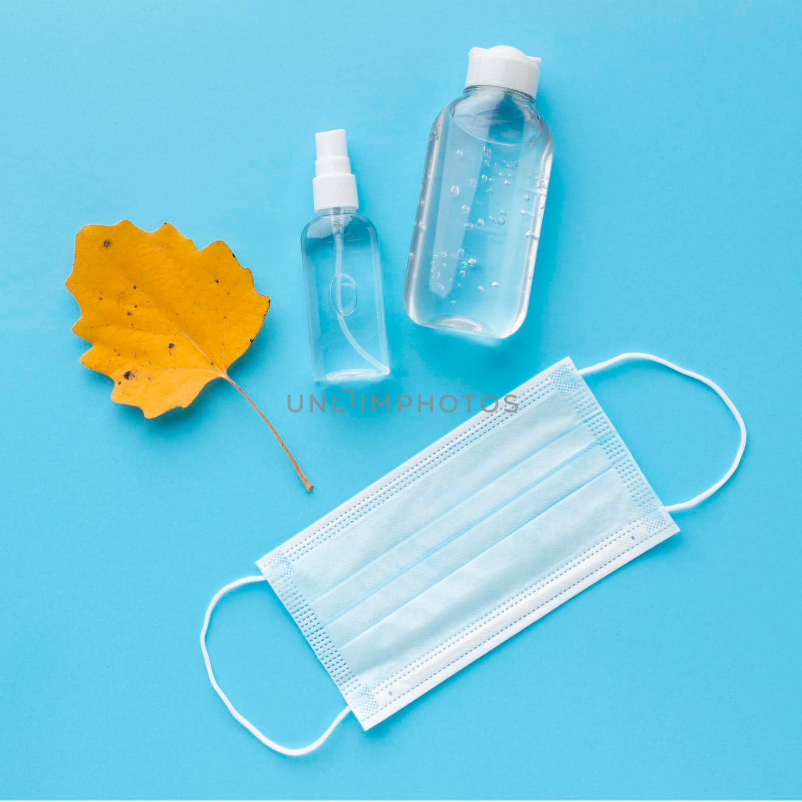 top view medical mask with hand sanitizer autumn leaf. High resolution photo
