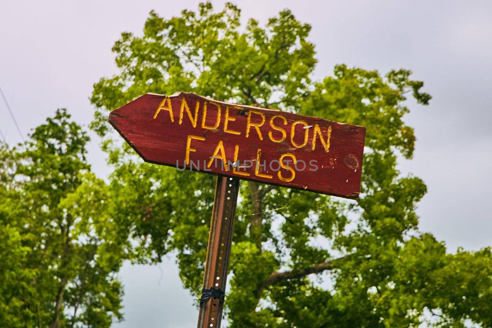 Image of Road sign for Anderson Falls with green trees in background
