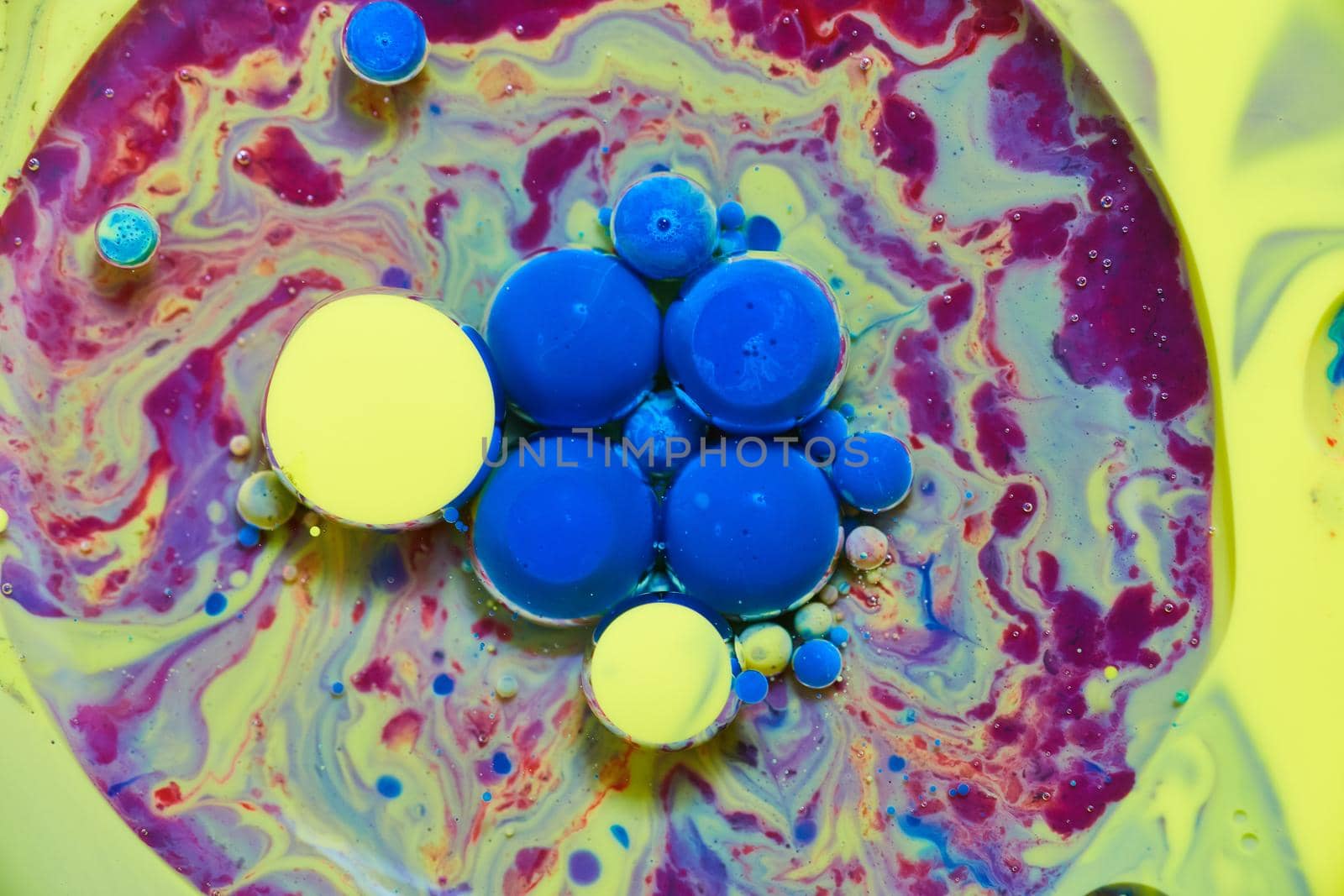 Image of Blue and yellow spheres floating on rainbow surface of silky liquid