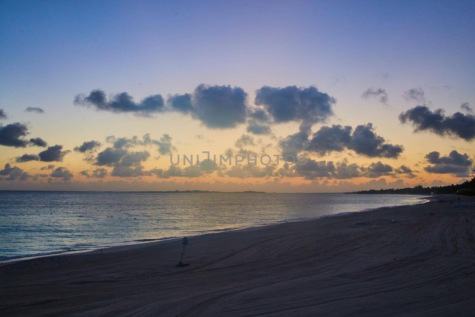 Image of Beach landscape of ocean with sunset and spotted clouds