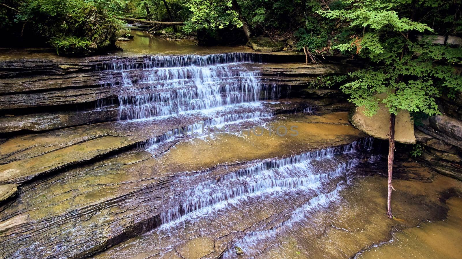 Image of Tiers of rock with waterfalls pouring over in woods