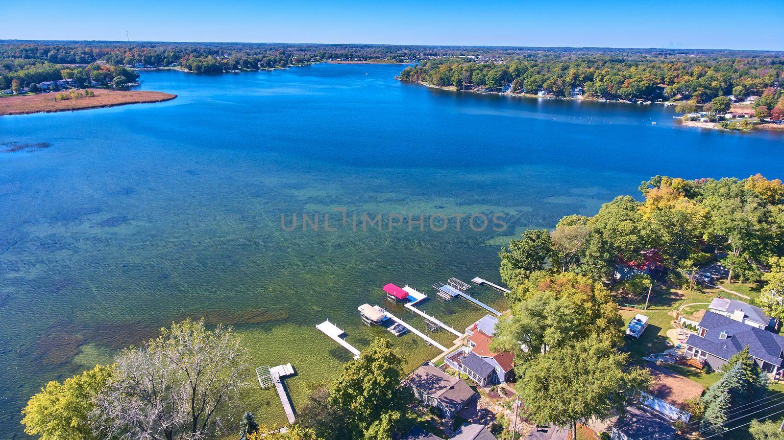 View above lake properties on bright blue lake with docks by njproductions