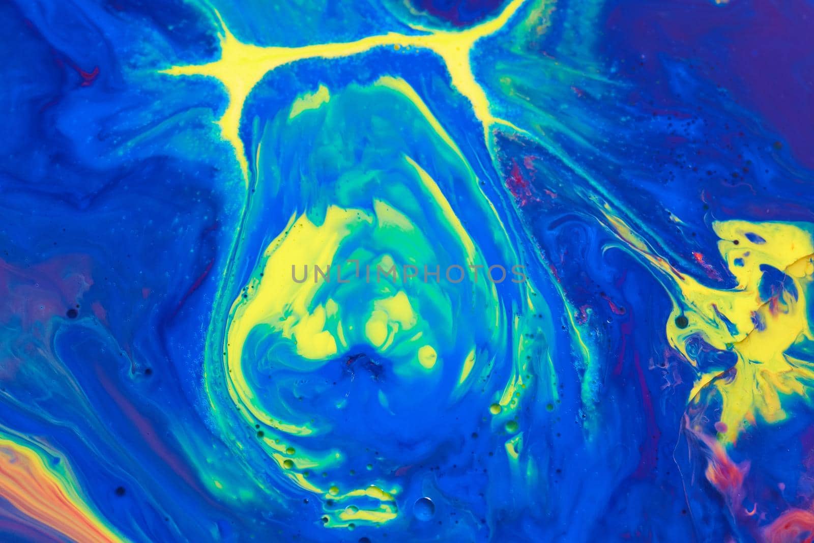 Image of Surface of liquid with colorful mix of blue and yellow to make green