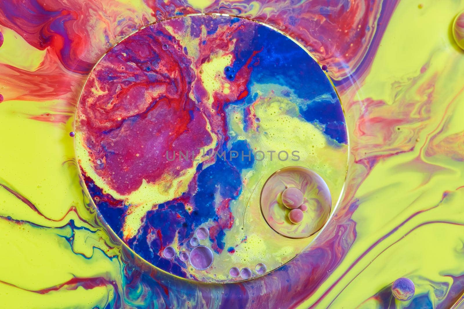 Image of Red, yellow, and blue colors on liquid surface with tiny orbs and circular patterns