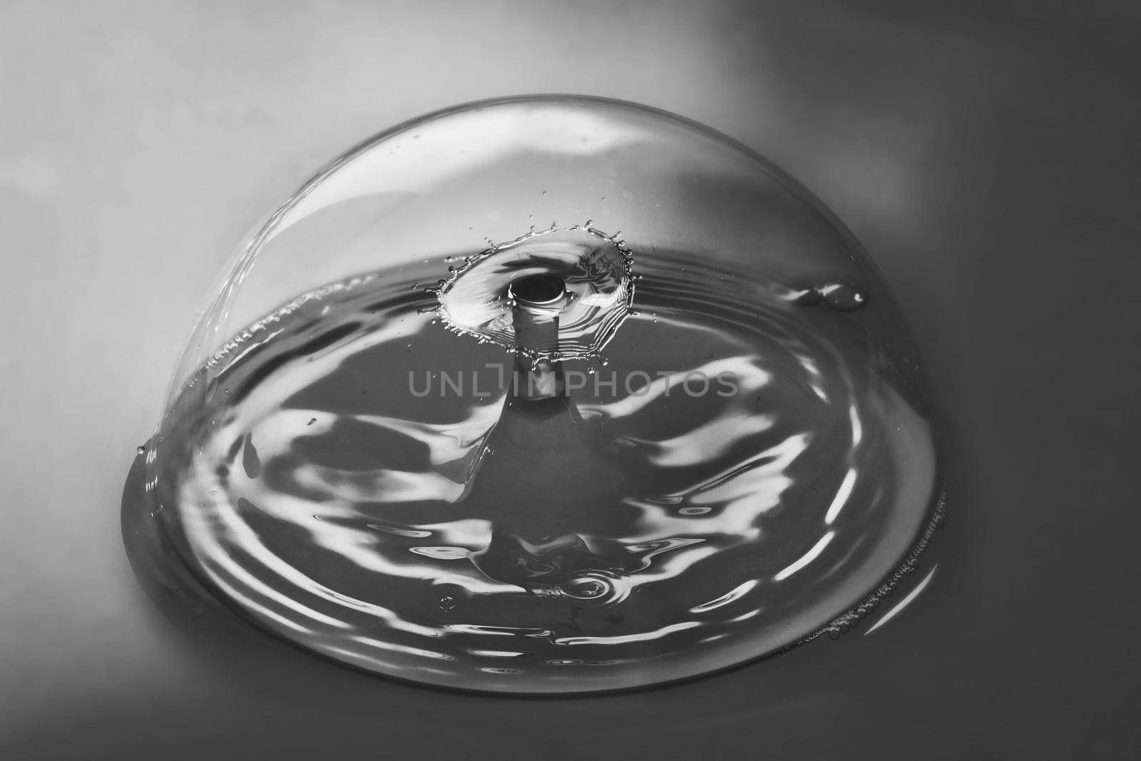 Image of Black and white of pristine bubble containing ripples from two water drops colliding in air