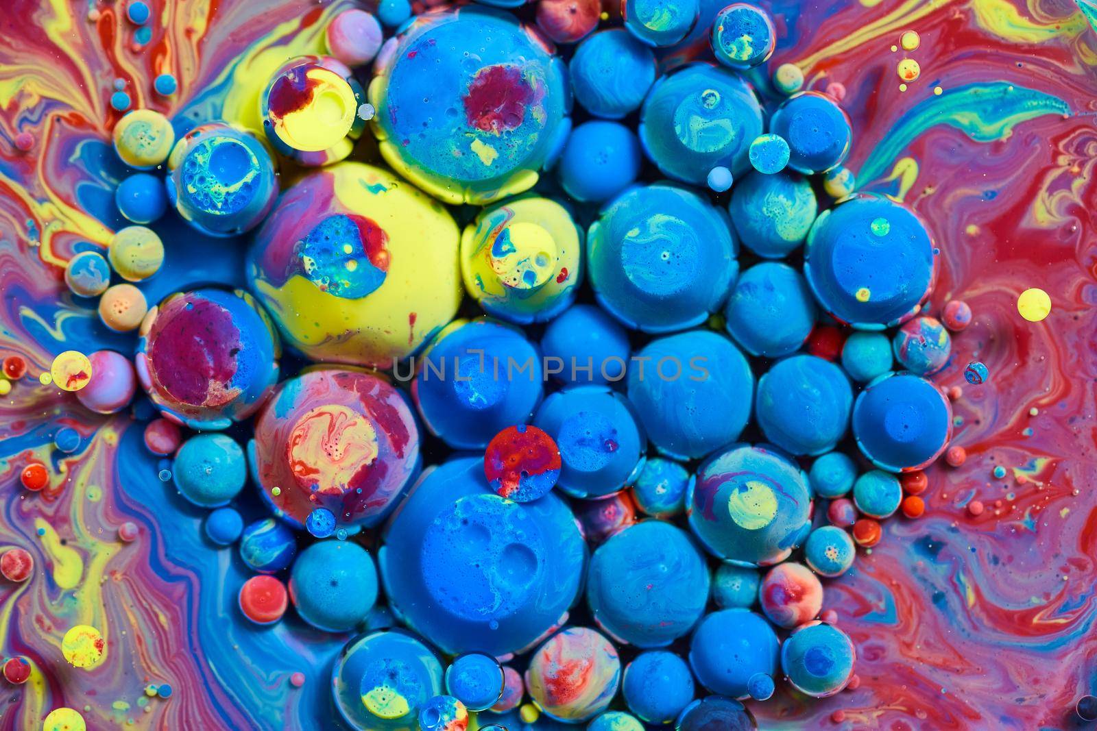 Image of Cluster of blue and rainbow spheres on surface of colorful liquid