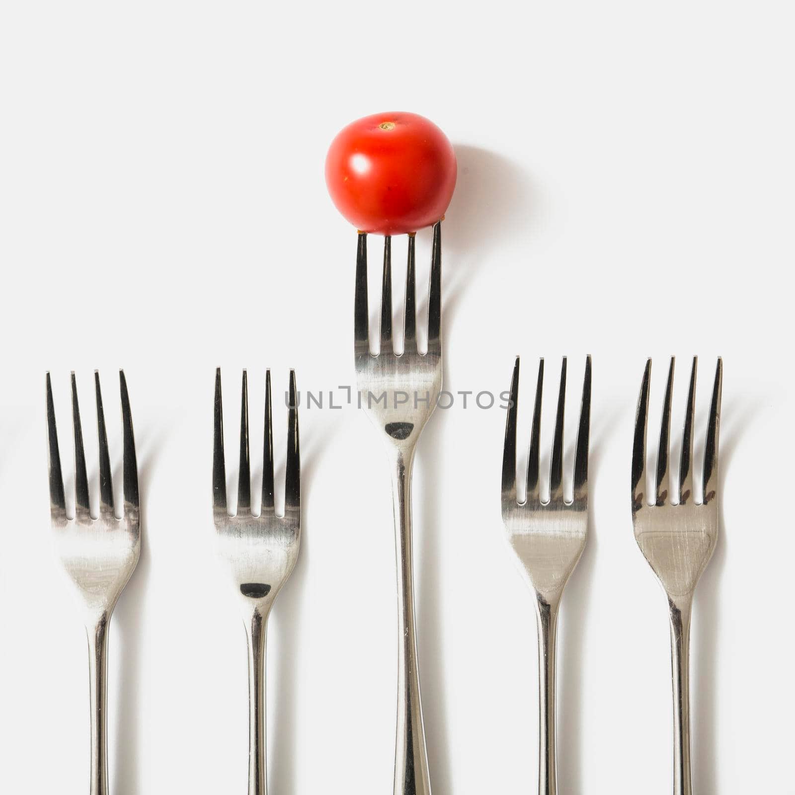 red cherry tomato fork against white background by Zahard