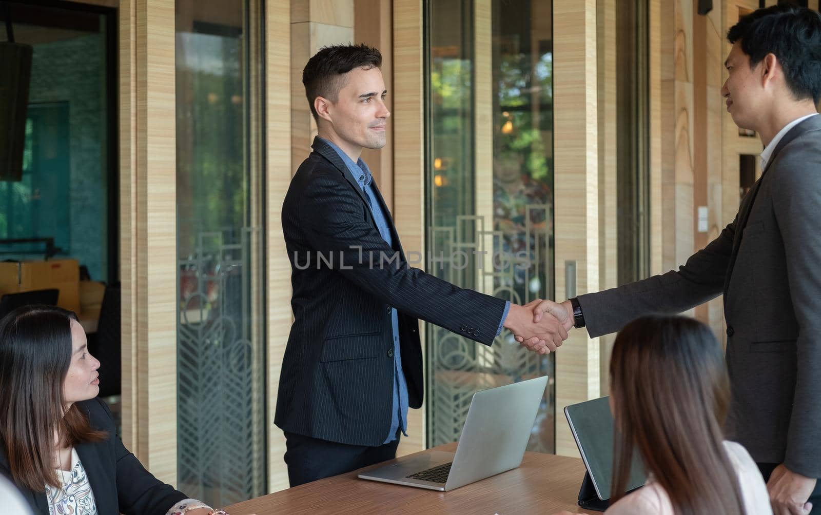 Group business people handshake at meeting table in office together with confident. Young businessman and businesswoman workers express agreement of investment deal by nateemee