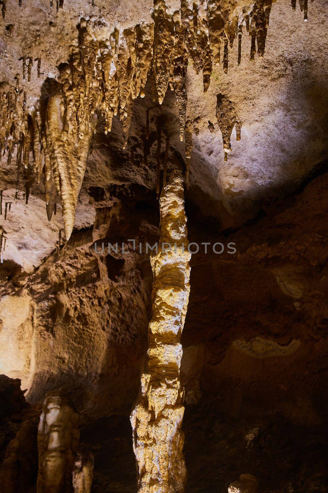 Large stalagmite and stalactites in golden cave by njproductions