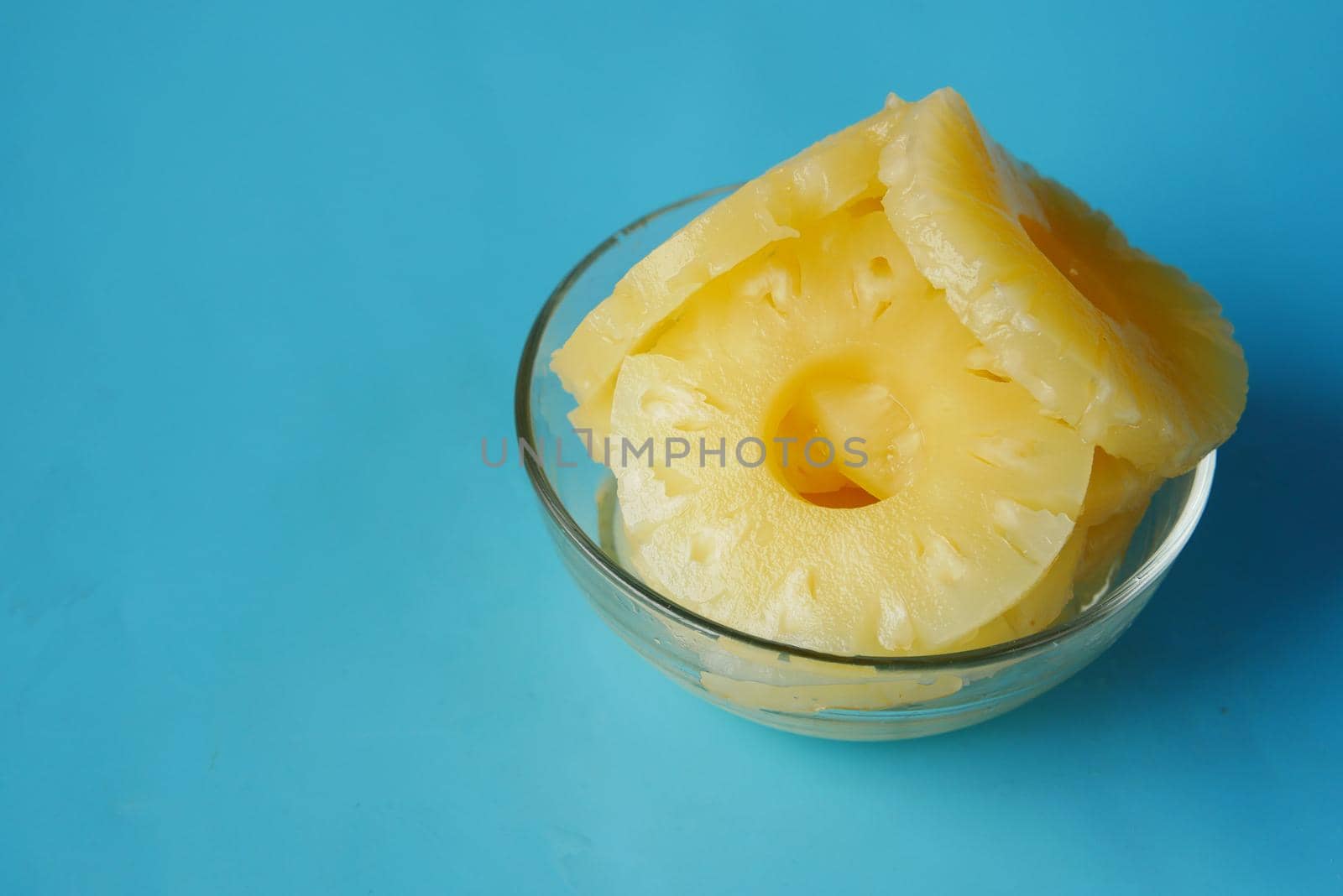 slice of pineapple in bowl on blue background by towfiq007