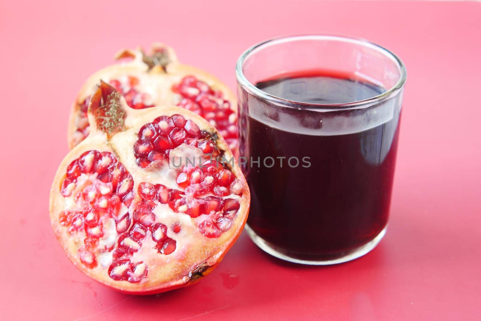 glass on pomegranate juice and fresh fruits on red background