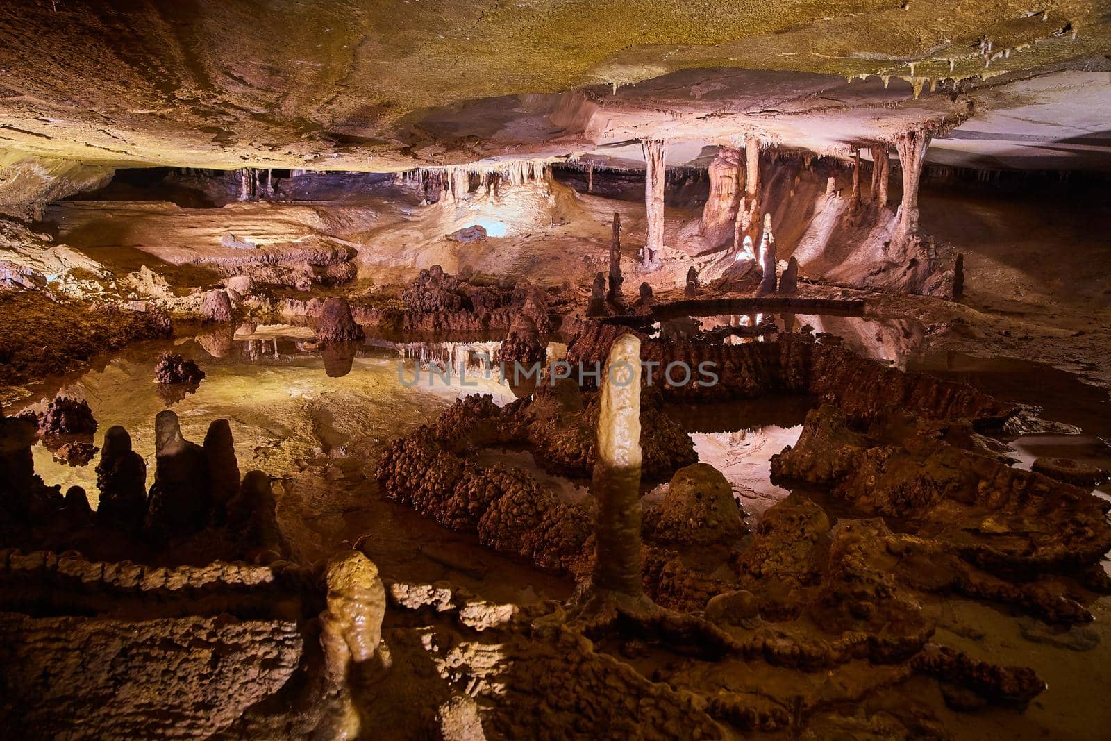 View of large open cave filled with reflective waters, stalagmites and stalactites by njproductions