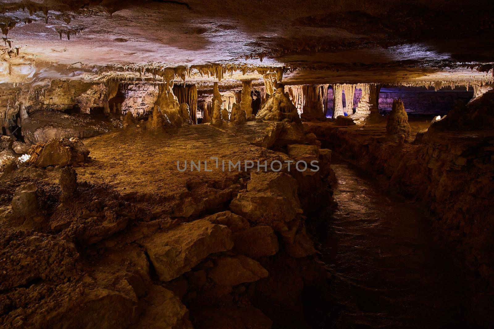 Narrow cave filled with formations of stalagmites and stalactites by njproductions