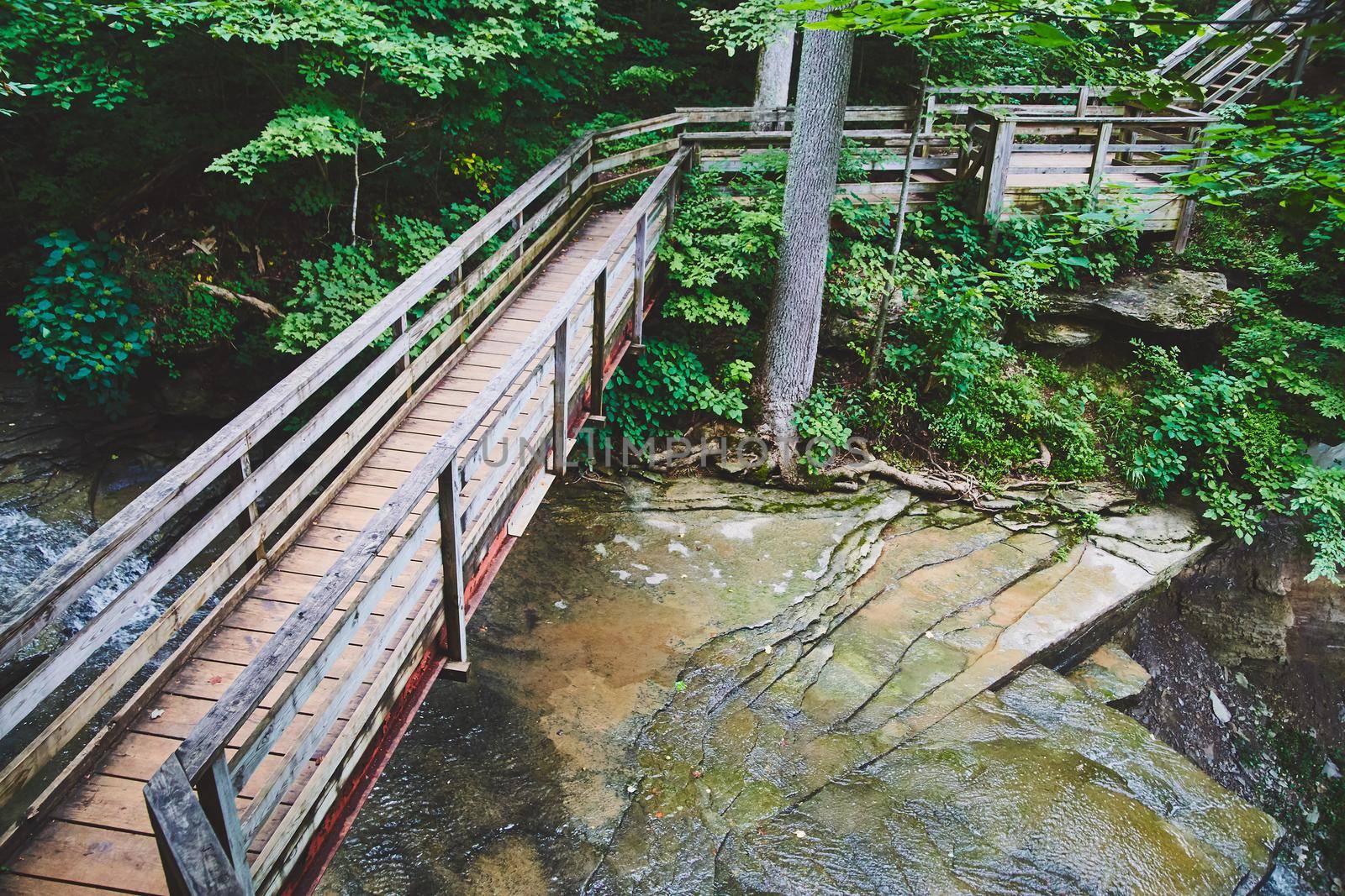 Walking bridge over shallow rock sheet river by njproductions