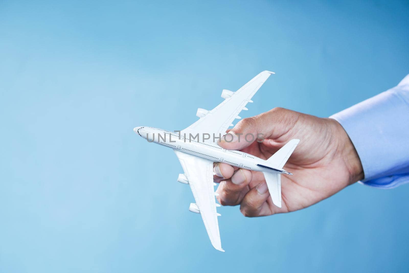 Hand holding toy plane over blue background ,