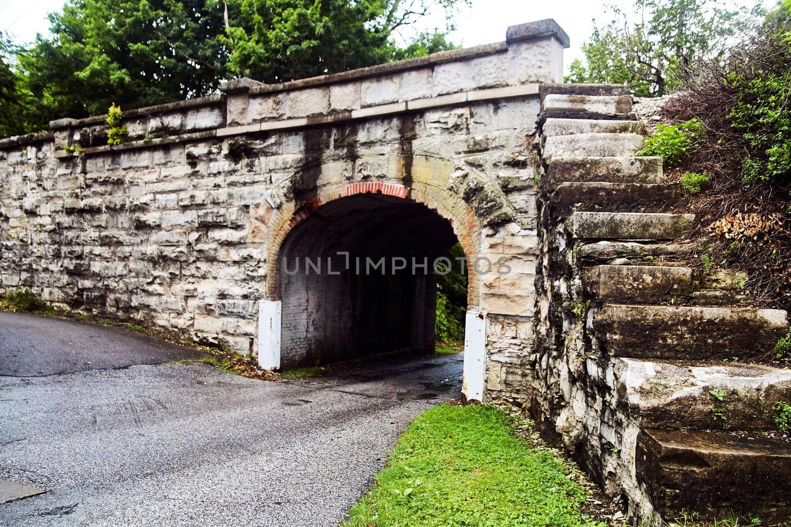 Small road going under stone tunnel with stone steps to the top by njproductions