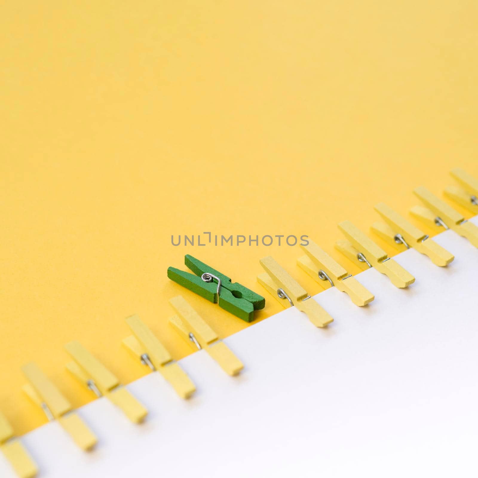 green clothespin surrounded by yellow ones by Zahard