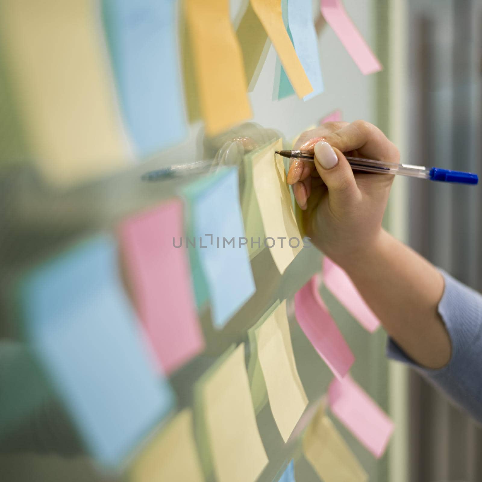 woman writing sticky notes office window. High resolution photo