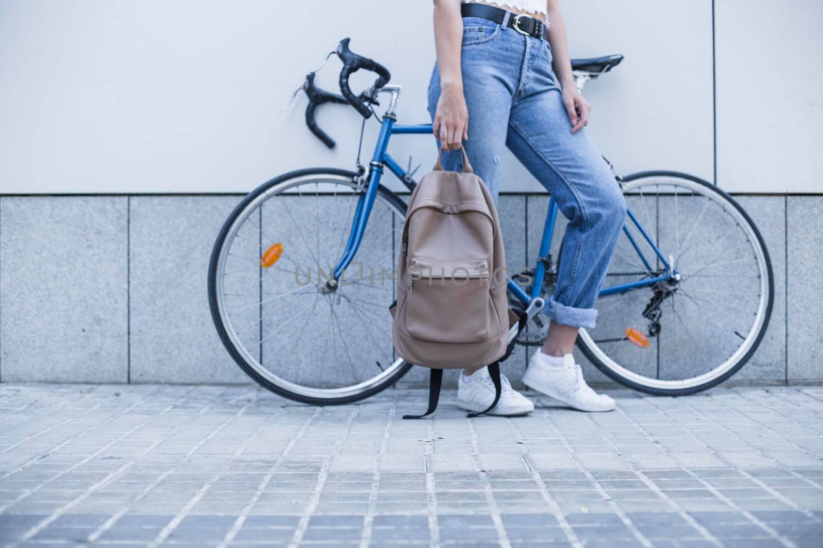 low section young woman standing near bicycle holding backpack. Beautiful photo