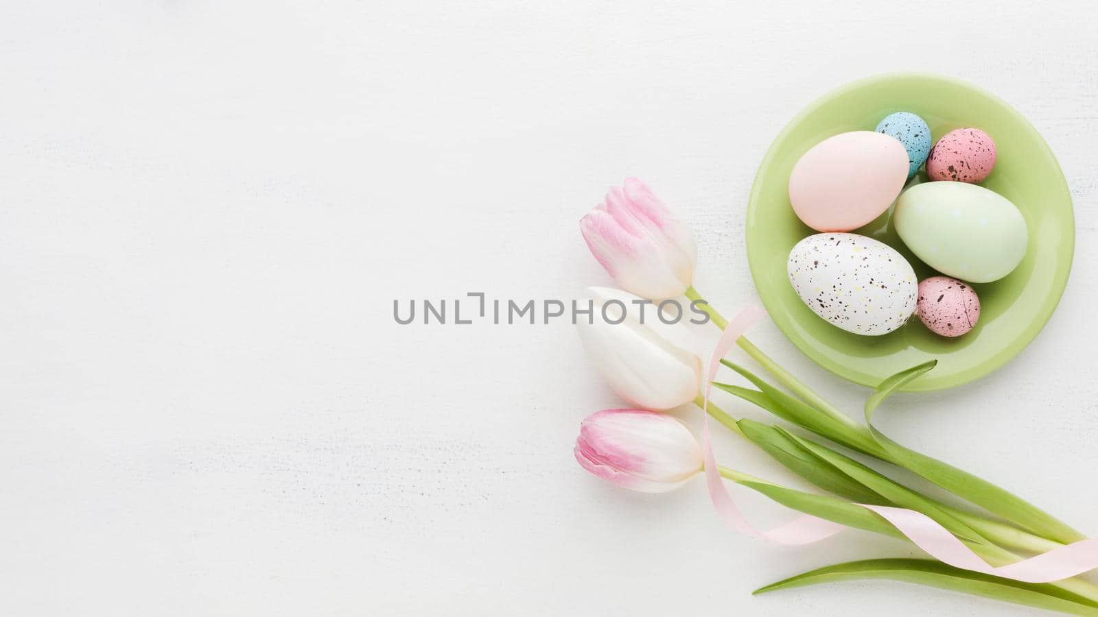 top view colorful easter eggs plate with tulips. High resolution photo