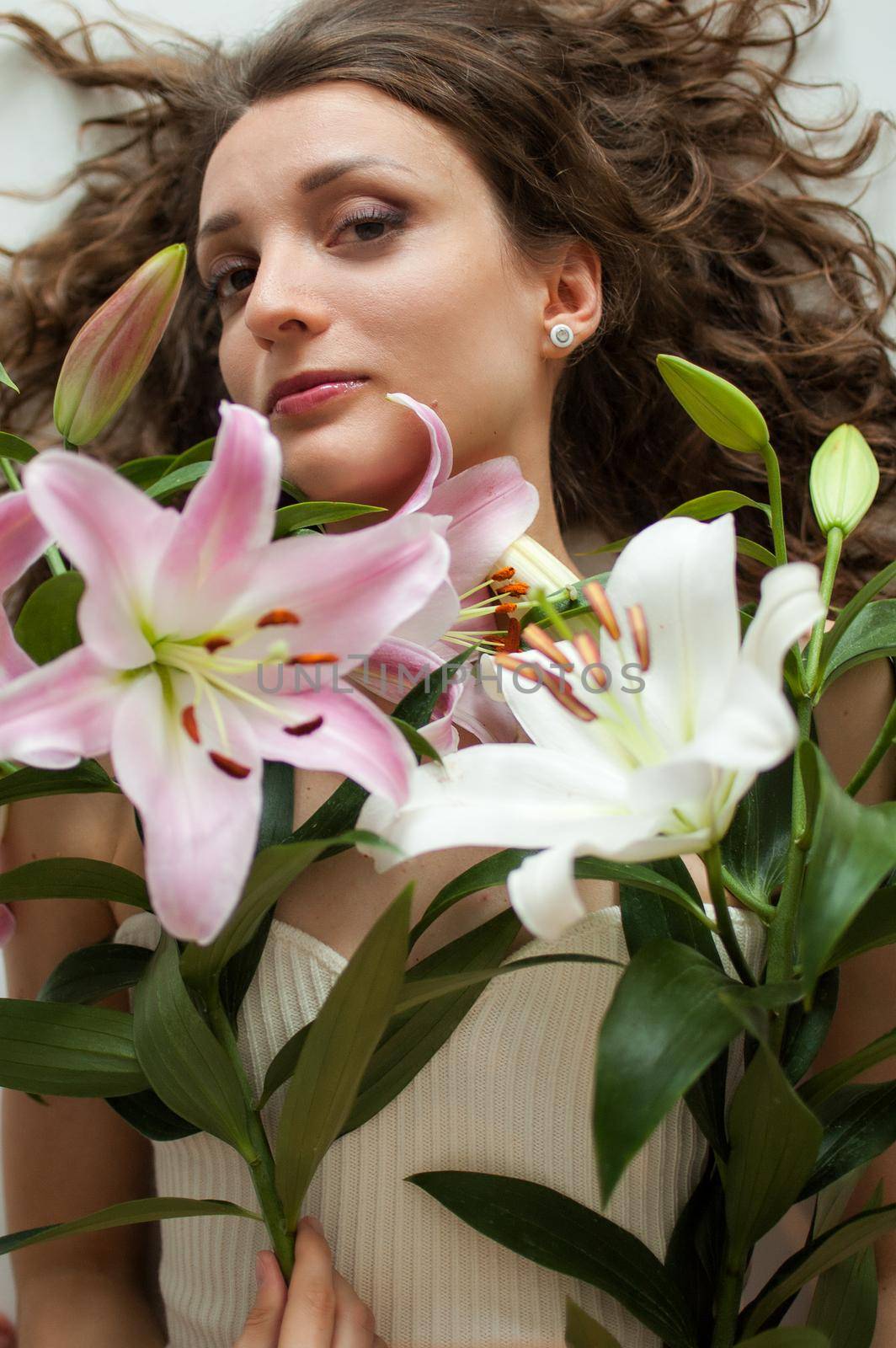 Top view of beautiful woman lying on the table with perfect bouquet of beautiful lilies, female portrait concept by balinska_lv