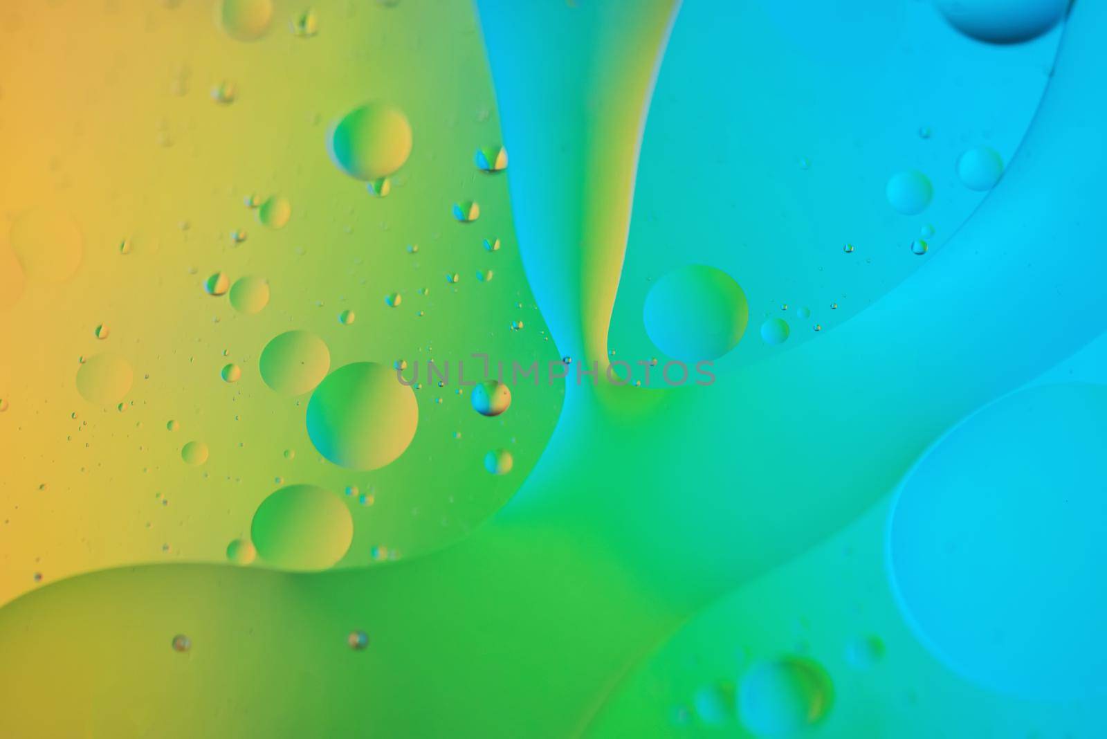 Colorful abstract background with oil drops on water. Yellow green blue color