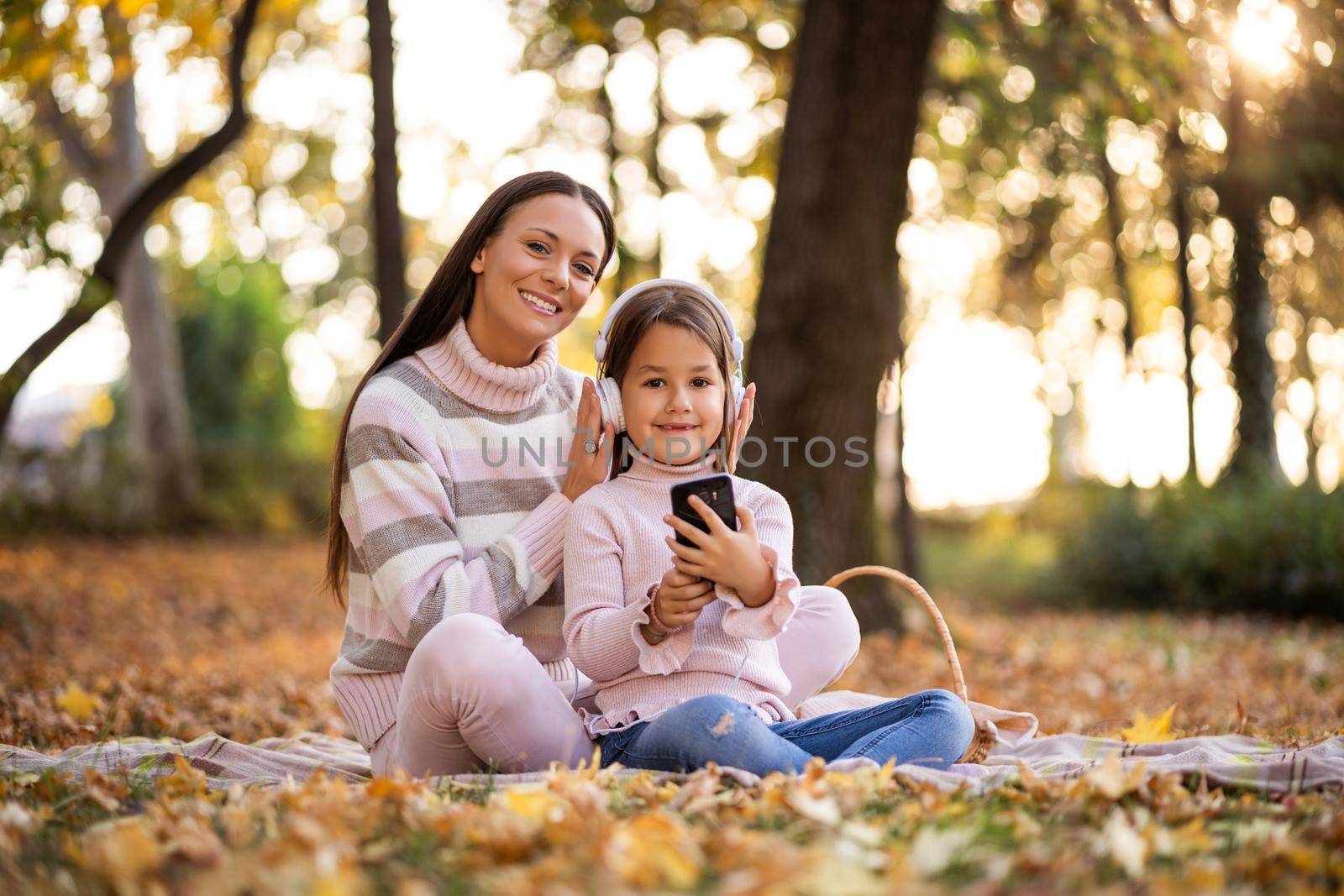 Mother and daughter enjoying autumn in park.