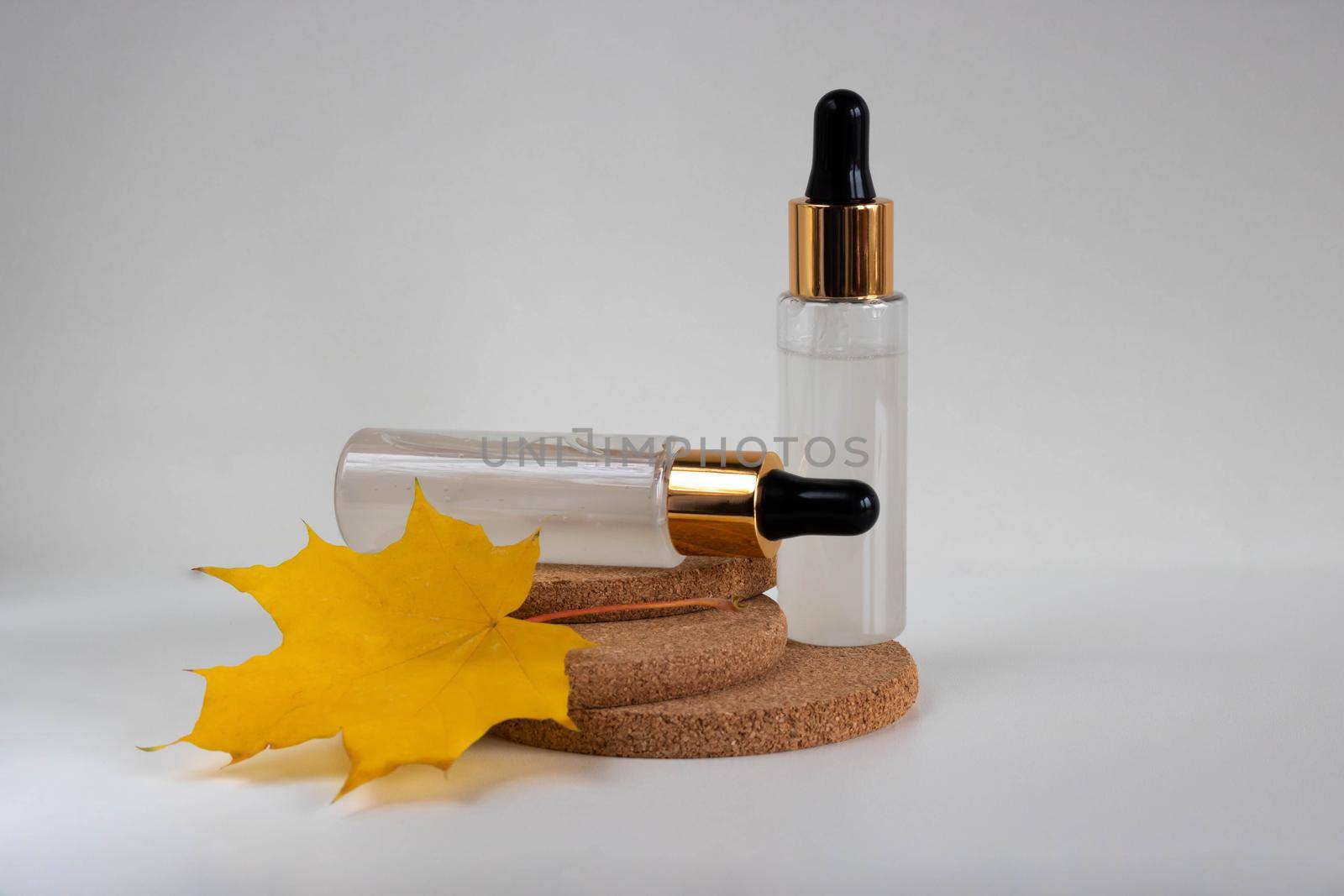 Two frosted bottles with a pipette, isolated on cork stands on a white background. The layout is suitable for cosmetics design.