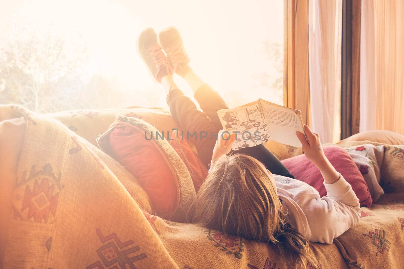 girl lying sofa reading book. High resolution photo