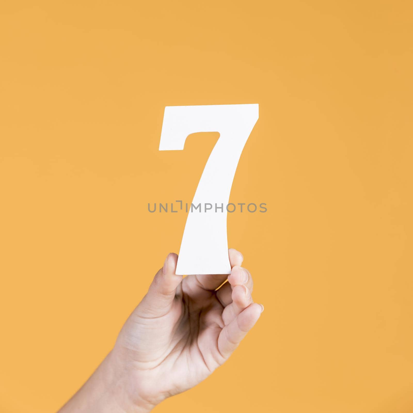 human hand holding number seven against yellow background. Resolution and high quality beautiful photo