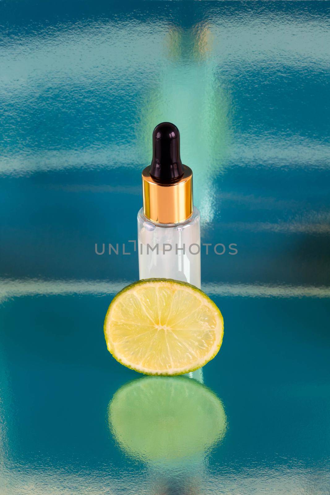 A piece of lime and a frosted bottle with an eyedropper, isolated on a glossy blue background. The layout is suitable for cosmetics design by lapushka62