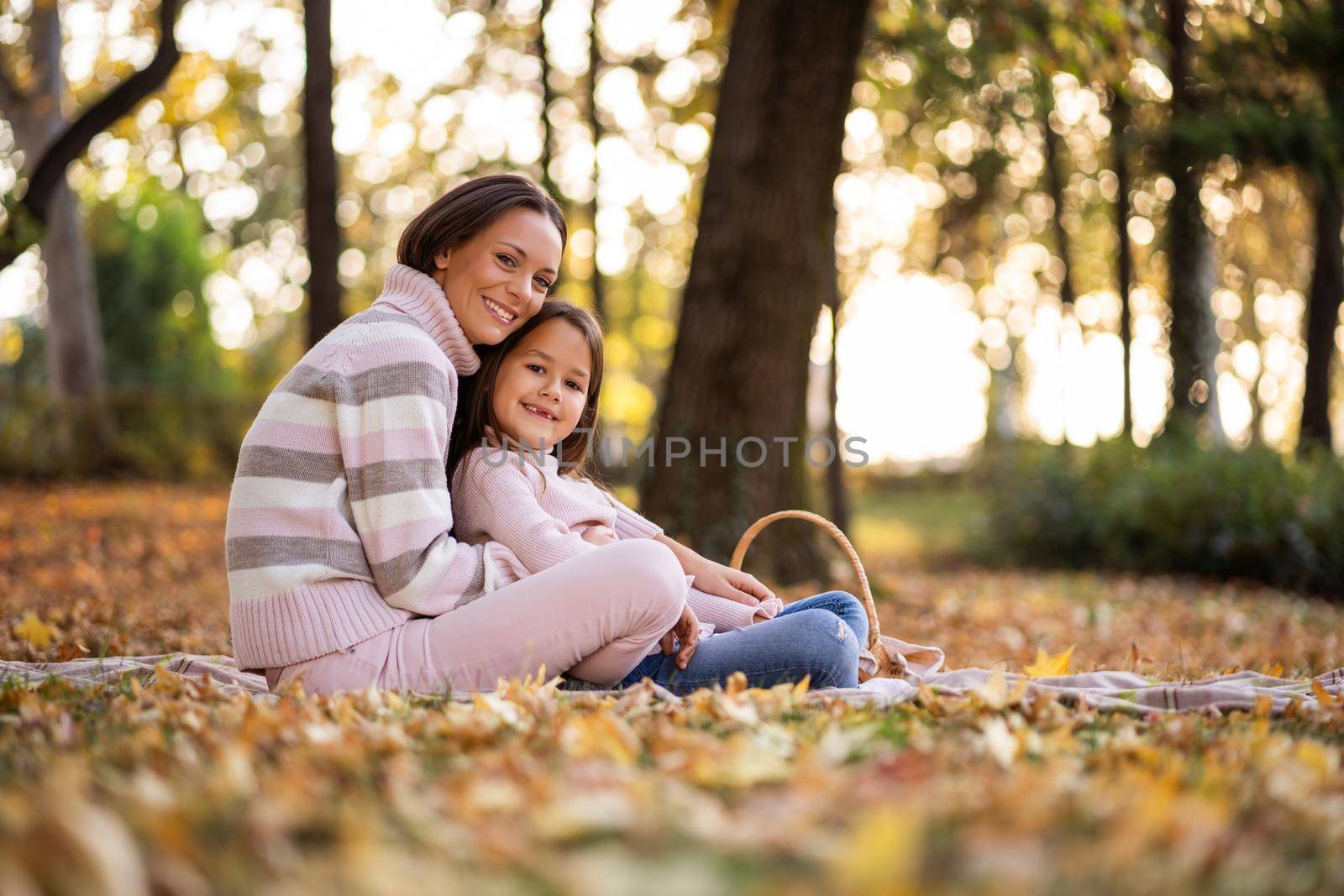 Mother and daughter enjoying autumn in park.