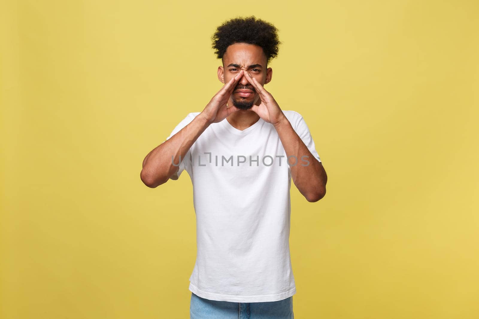 positive young black guy, student, worker employee screams mouth wide open and putting his hands to his face as mouthpiece. Portrait on white background in casual clothing