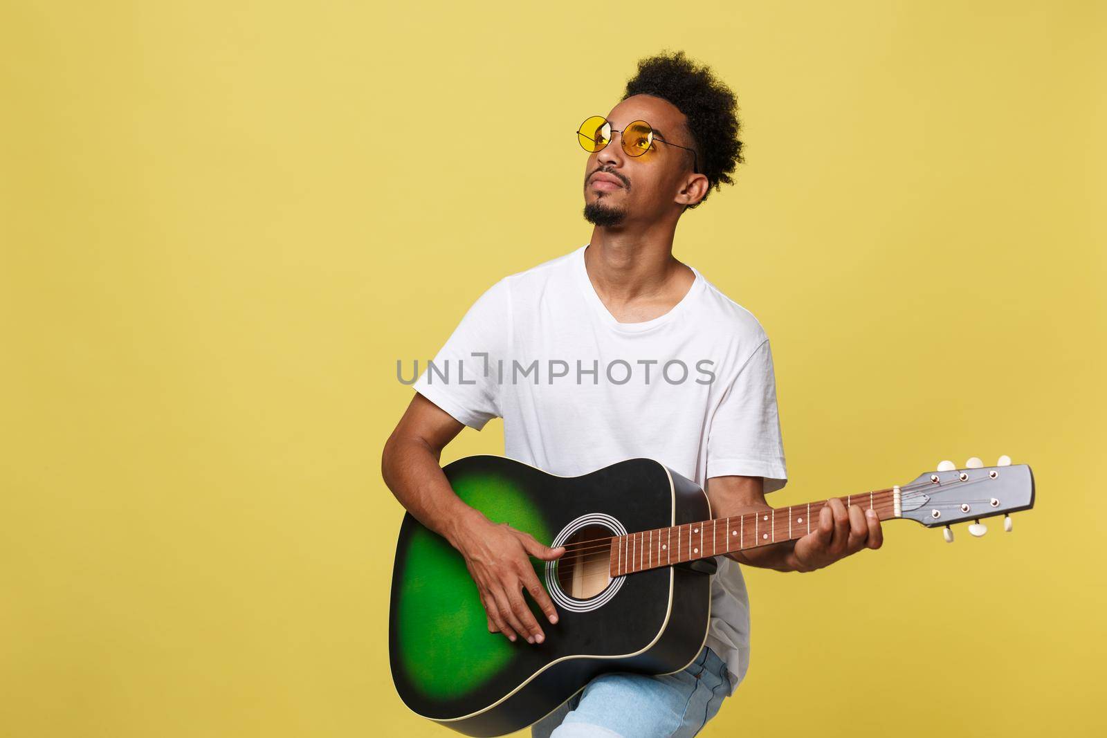 Happy african american musician man posing with a guitar, over golden yellow background. by Benzoix