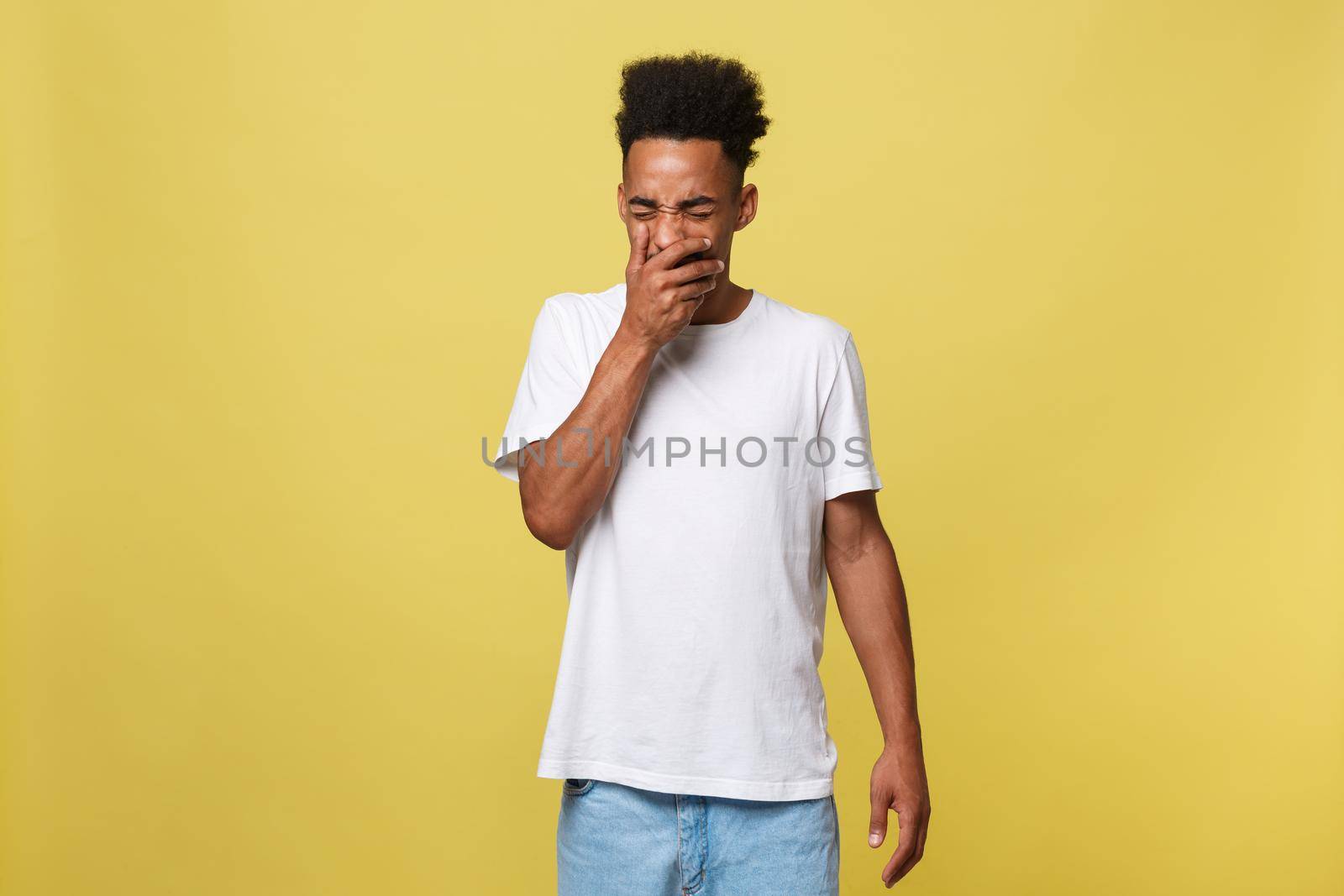 Portrait of attractive sleepy african-american male model in trendy black hat, yawning, covering mouth with palm and stretching, feeling tired and sleepy over yellow background by Benzoix