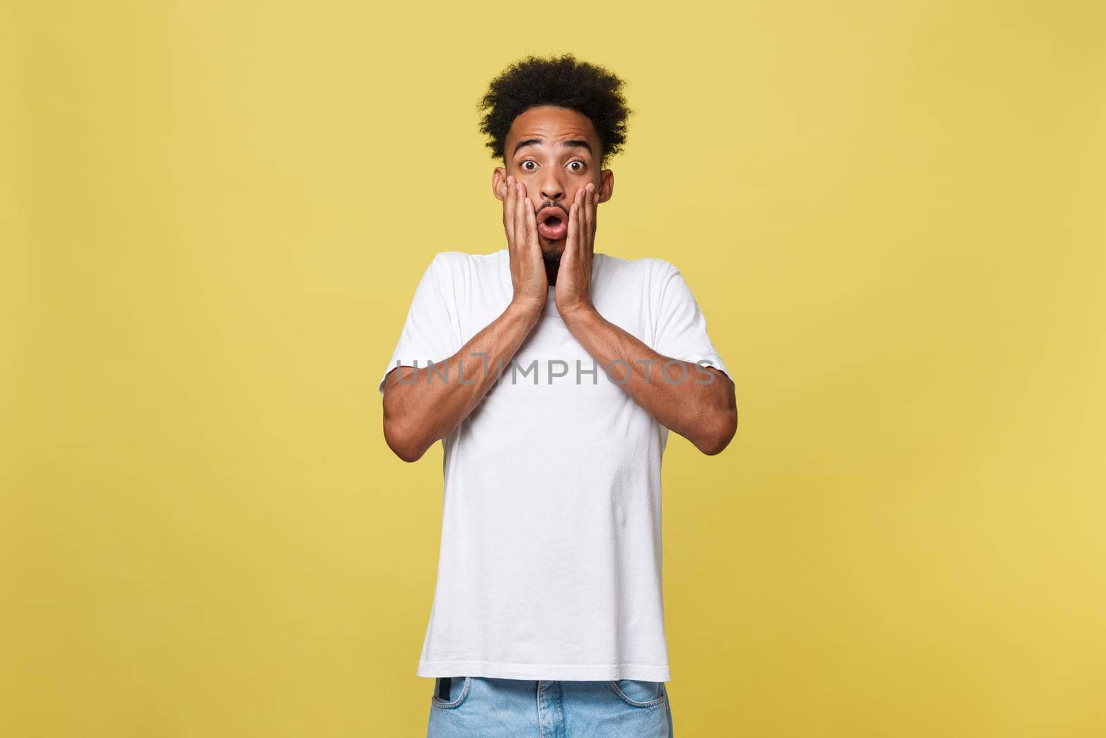 Emotional and People Concept - Portrait of excited young African American man screaming in shock and amazement holding hands on head. by Benzoix