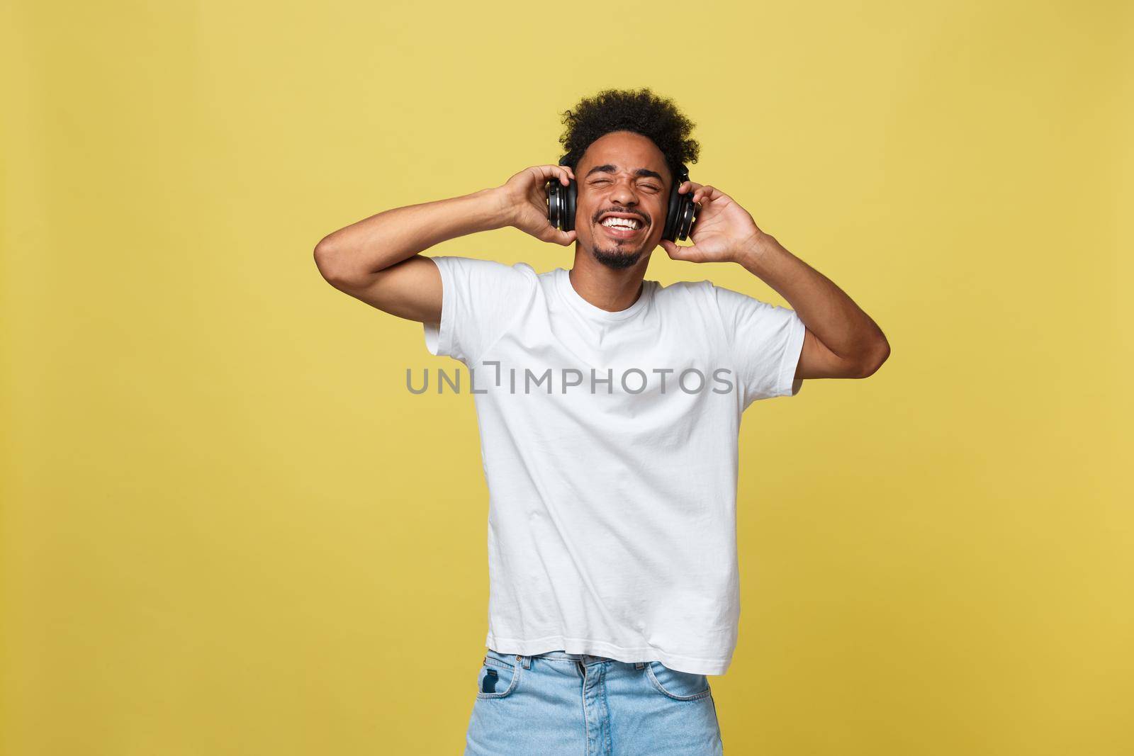 Portrait good-looking african male model with beard listening to music. Isolated over yellow background by Benzoix