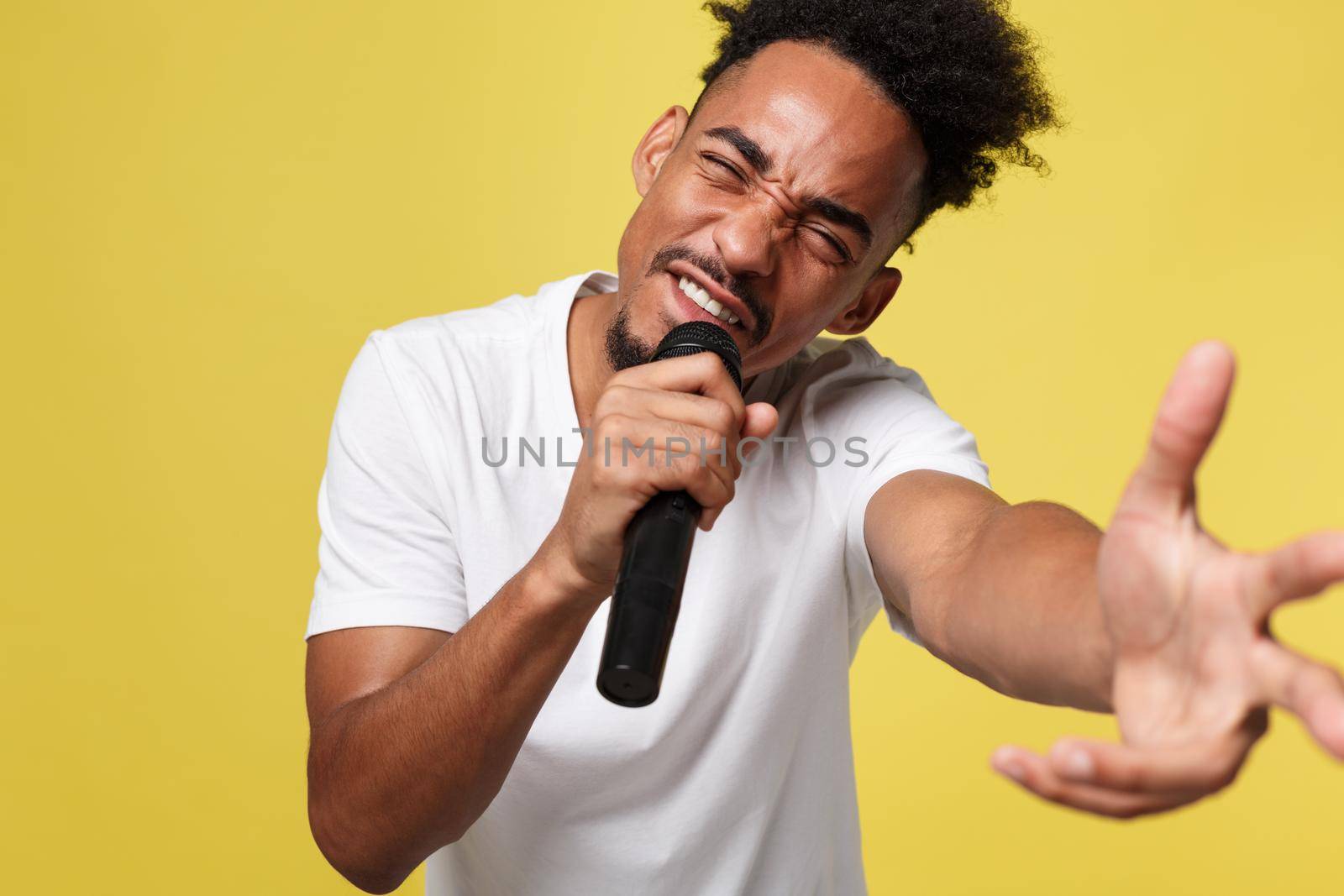 Stylish afro american man singing into microphone isolated on a yellow gold background by Benzoix