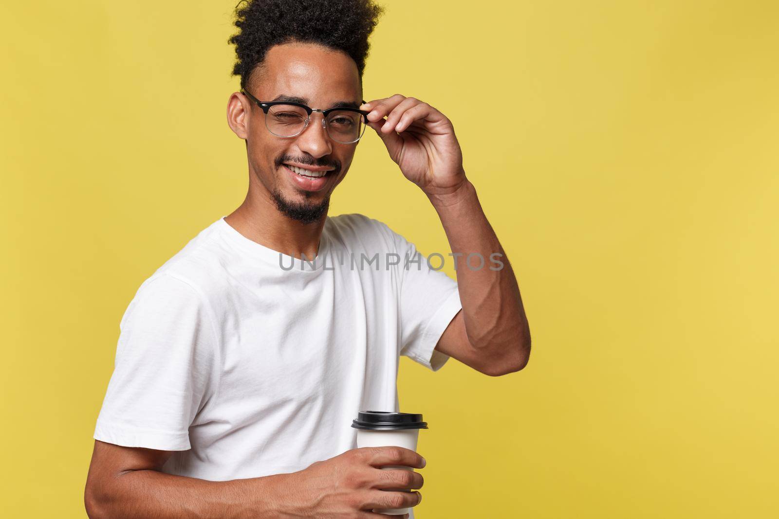 Stylish young afro american man holding cup of take away coffee isolated over yellow background by Benzoix