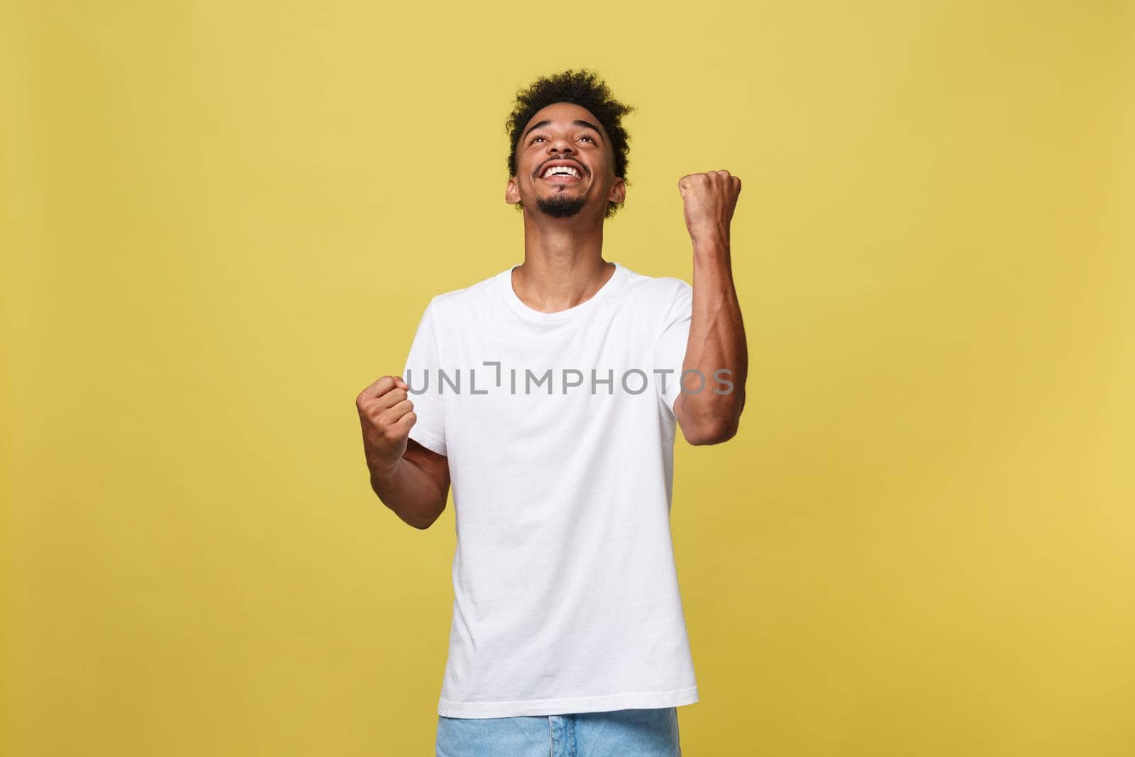 Portrait of a cheerful young man shouting with arms raised in success.