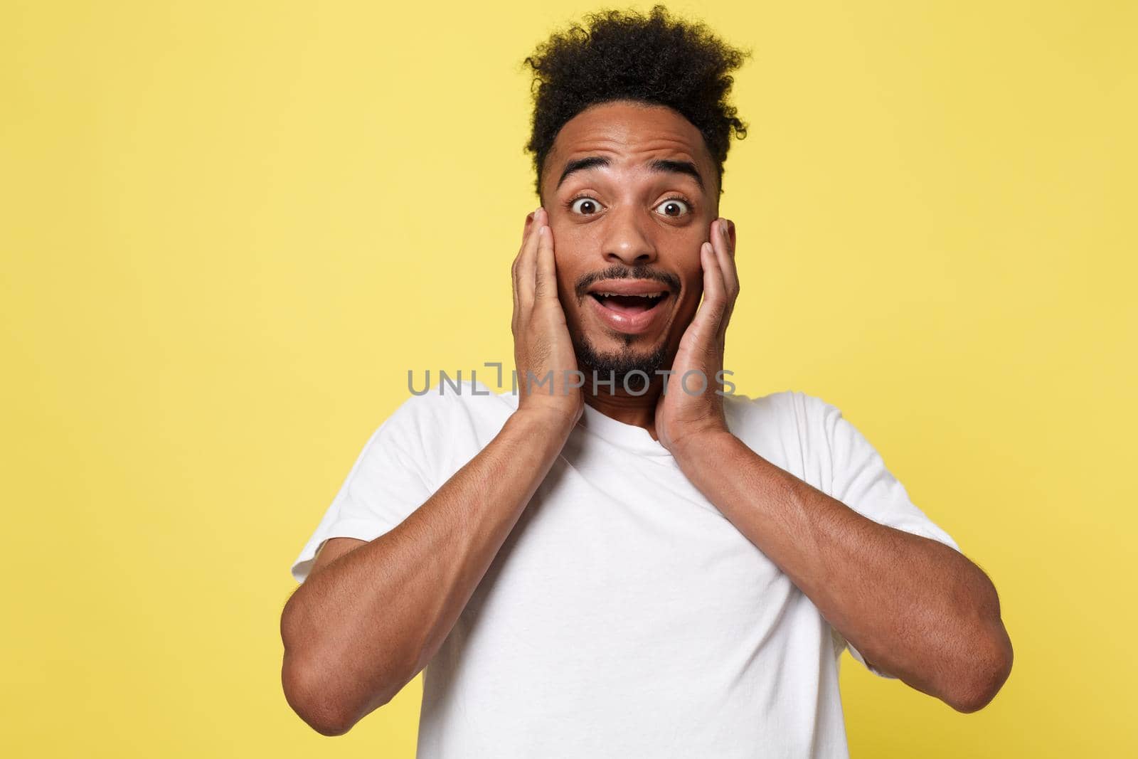 Emotional and People Concept - Portrait of excited young African American man screaming in shock and amazement holding hands on head. by Benzoix